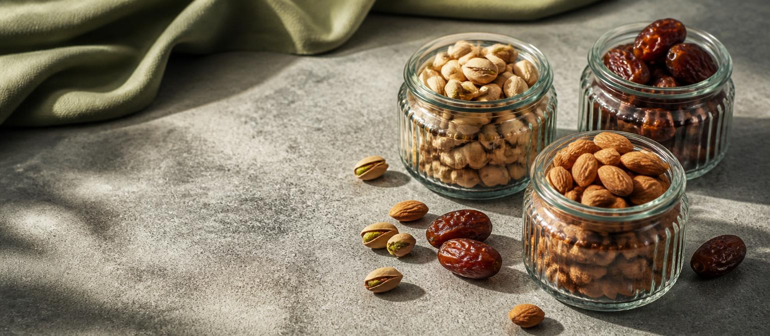 Pistachios, dates and almonds in glass jars on a stone slab
